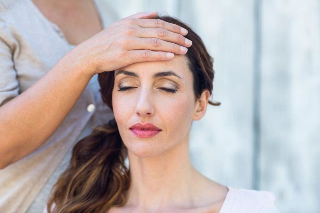 A woman is holding her hands up to the side of her face.