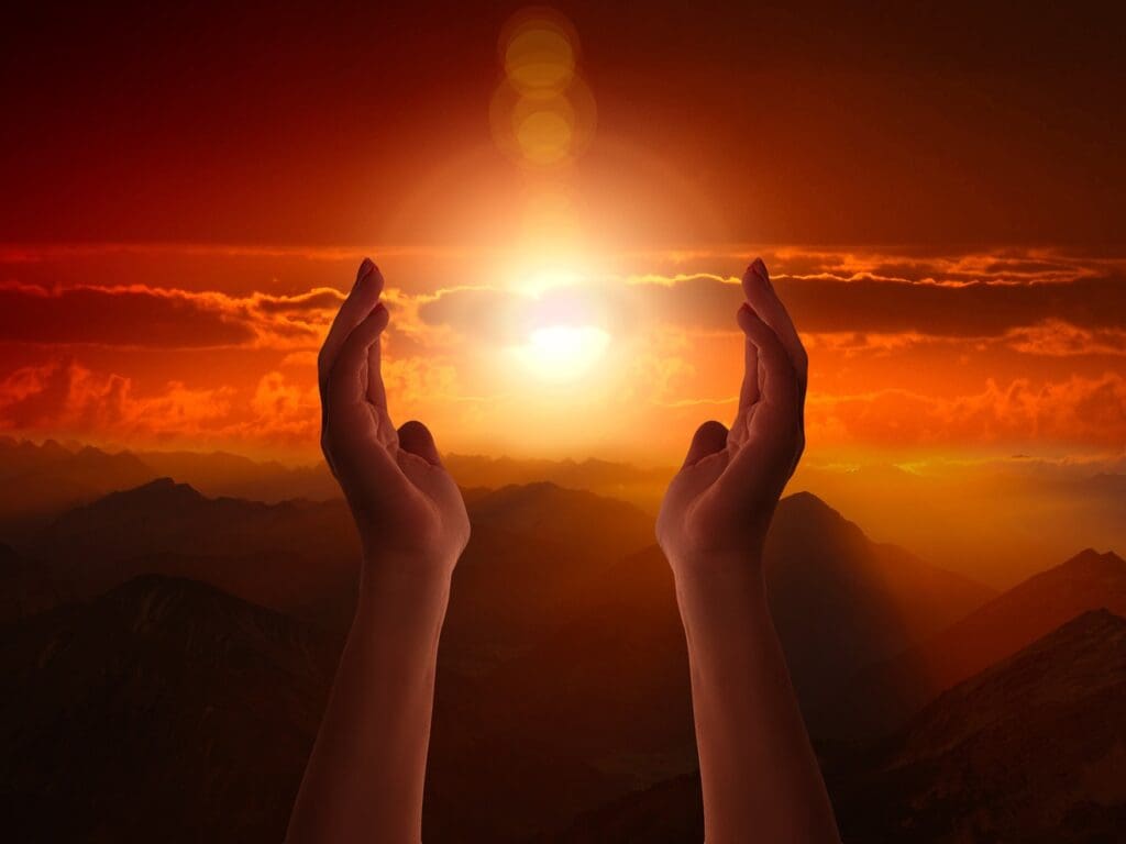 A person 's hands reaching up towards the sun.